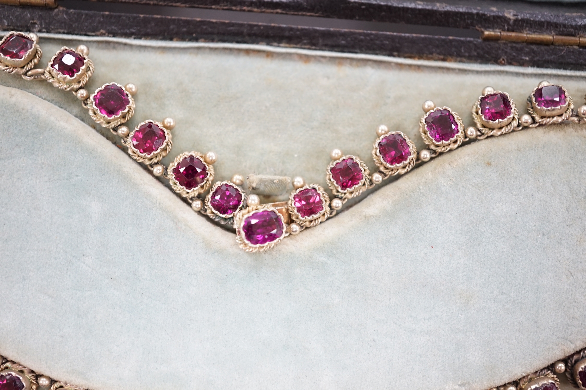 A cased 19th century gilt white metal and graduated oval and square cut garnet set fringe necklace, lacking drop, 37cm.